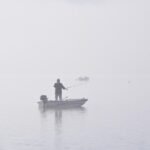 Barco pesquero navegando en un lago con niebla representando la presión de no saber qué hacer con tu vida