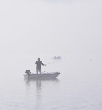 Barco pesquero navegando en un lago con niebla representando la presión de no saber qué hacer con tu vida