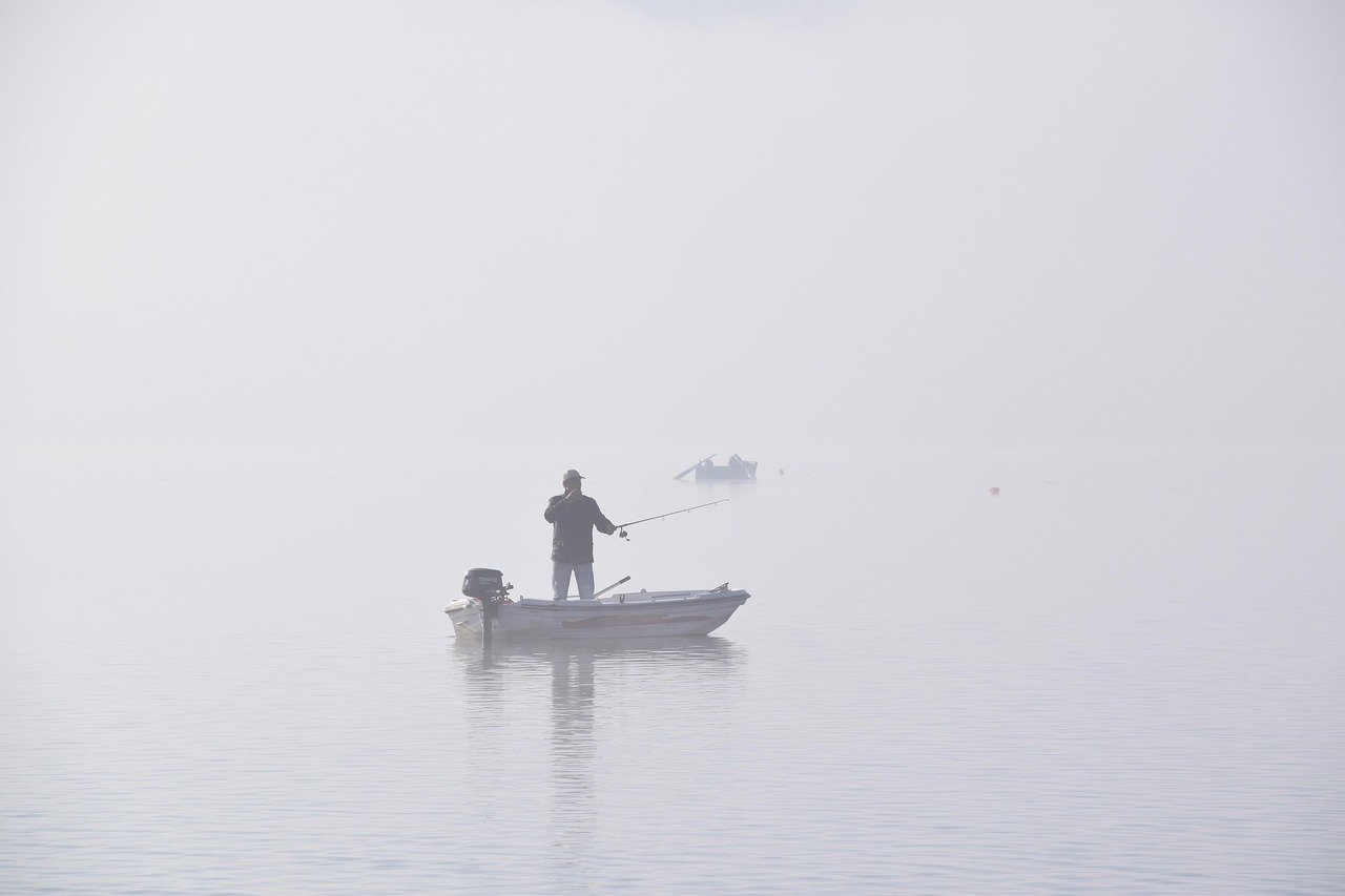 Barco pesquero navegando en un lago con niebla representando la presión de no saber qué hacer con tu vida