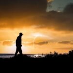 Persona reflexionando sobre su camino en la vida, pensando en proyectos propios y emprendimiento, mientras mira al horizonte.