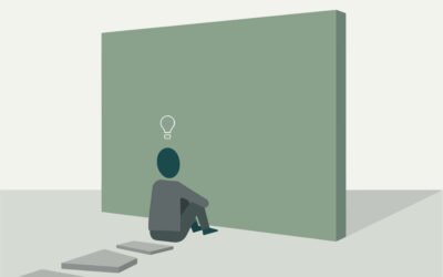 Persona sentada reflexionando frente a una pared que simboliza bloqueo mental y parálisis por análisis